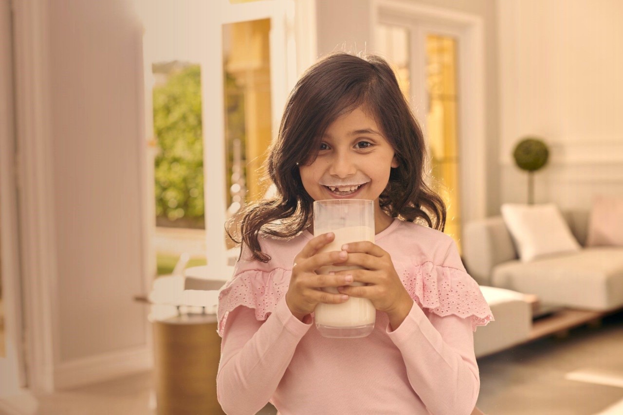 Happy girl drinking Anchor milk